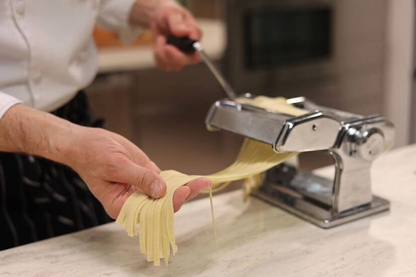 Chef making pasta noodles in a pasta maker 