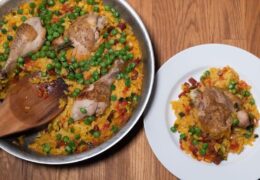 A pan full of paella with a wooden spoon
