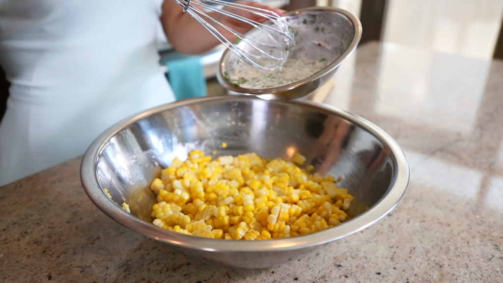 Once the corn has cooled, add the sauce, toss to coat and then add in the jalapeno, tomato and the cheese.